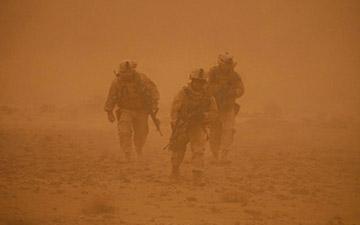 三个士兵在沙尘暴中行走
